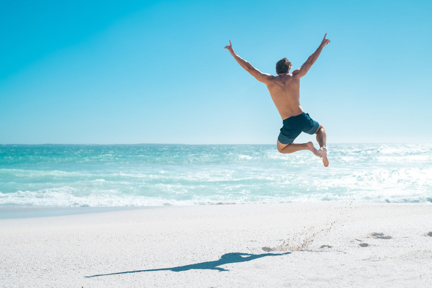 Guy jumping high on the beach